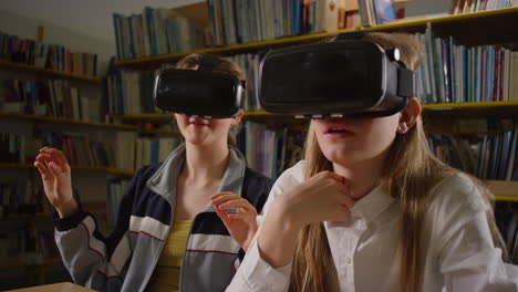 Zwei-Mädchen-Nutzen-Neue-Technologie-In-Der-Bibliothek,-Tragen-VR-Headsets-Und-Handhelds