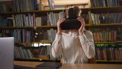 Girl-using-devices-in-the-library,-a-laptop-and-VR-headset,-handheld-shot
