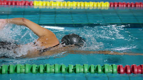 Powerful-female-swimmer-swimming-breaststroke-at-speed,-tracking-shot