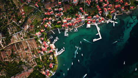 Slow-motion-overview-of-boats-entering-dock-at-Ilovik-island-Croatia,-drone-top-down