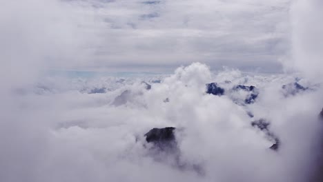 Beautiful-cinematic-aerial-flying-through-scenic-white-clouds-in-heavenly-sky-with-mountain-top-peaks-looking-through-cloudscape