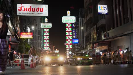 Taxis-Y-Automóviles-En-El-Tráfico-En-El-Barrio-Chino-De-Bangkok-Por-La-Noche-Con-Muchas-Luces-Y-Gente.