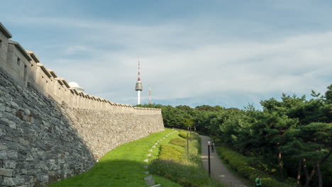 N-Seoul-Tower-Oder-Namsan-Tower-Und-Seouler-Stadtmauer-Hanyangdoseong,-Zeitraffer-Von-Koreanern-Und-Touristen,-Die-Auf-Einem-Fußweg-In-Einem-Grünen-Bergpark-Spazieren-–-Zoom-In-Bewegung