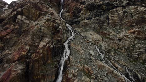 Increíble-Vuelo-De-Drones-Sobre-El-Agua-Y-Una-Cascada-Que-Fluye-En-El-Glaciarfelaria-En-Valmalenco-De-Valtellina,-Italia