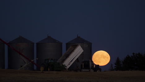 Telephoto-timelapse-of-full-moon-rising-behind-grain-silos-during-harvest