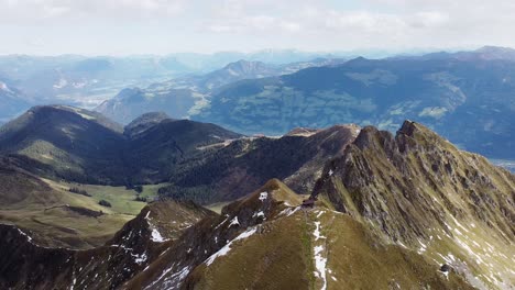 Filmische-Luftaufnahme-Des-Alpengipfels-Mit-Alter-Holzkapelle-Auf-Steilem-Gipfel