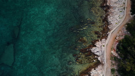 Aerial-bird's-eye-view-of-white-rugged-rocky-coastline-fading-to-turquoise-blue-water