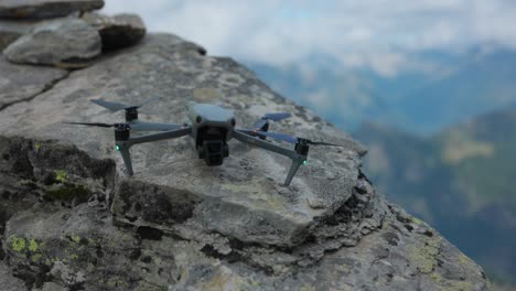 Close-up-of-DJI-Air-3-drone-on-rock-with-Valmalenco-mountains-in-background,-Italy