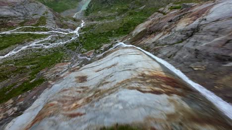Freestyle-drone-flight-over-water-stream-flowing-at-Fellaria-glacier-in-Valmalenco-of-Valtellina,-Italy