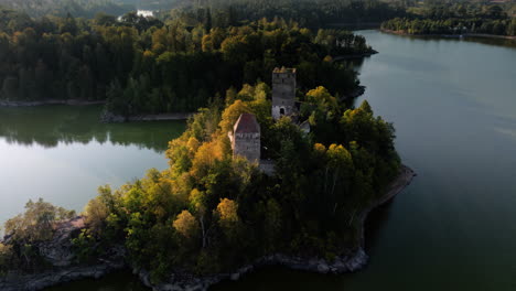Aerial-orbit-around-Ottenstein-castle-ruins,-cinematic-sun-flare-and-long-shadows-on-water
