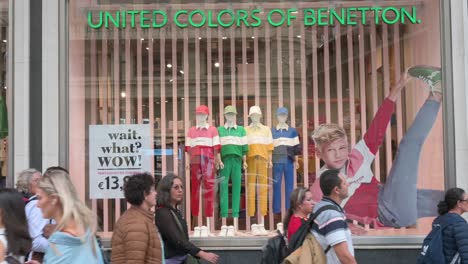 Pedestrians-and-shoppers-walk-past-the-Italian-fashion-brand-United-Colors-of-Benetton-store-in-Spain