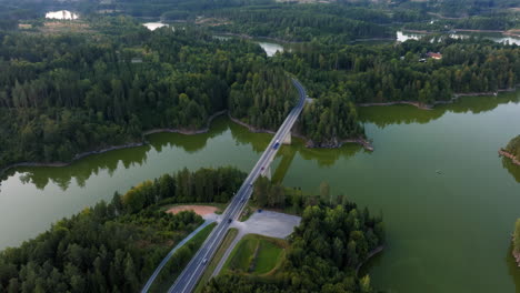 Cars-rush-across-bridge-spanning-Stausee-Ottenstein-reservoir-in-the-evening,-Austria,-drone-view