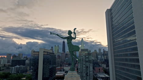 Aerial-view-ascending-in-front-of-the-Spirit-of-Progress-statue,-dusk-in-Chicago,-USA