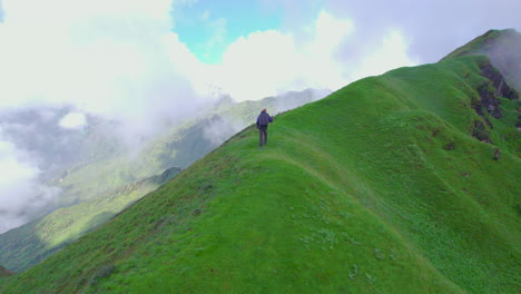 Nepali-solo-trekker-walks-green-hills-of-Nepal-carrying-a-stick,-Drone-shot,-cloudy-sky,-scenic-beauty-landscapes,-heavenly-nature