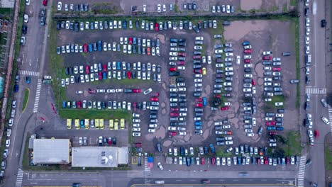 Aerial-timelapse-of-a-rustic-parking-lot-after-the-rain,-foggy-morning,-dominance-of-white-cars