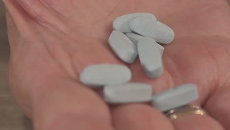 senior-citizen-holds-a-handful-of-expensive-blue-medicine-pills