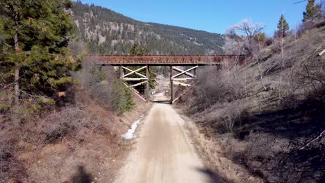 Okanagan-Rail-Trail-Drone-Flies-Under-Old-Wooden-Trestle-Walking-Bridge