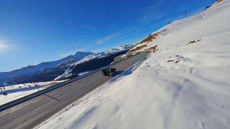 FPV-Luftverfolgung-Eines-Fahrzeugs,-Das-Auf-Einer-Malerischen-Straße-In-Einer-Schneebedeckten-Berglandschaft-Fährt