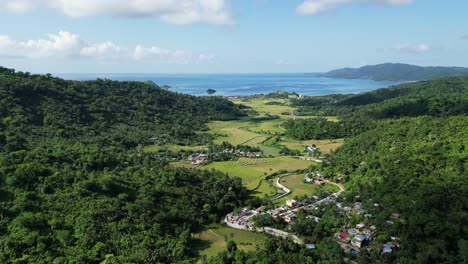 Aerial-View-Of-Town-Surrounded-By-Green-Mountains-Overlooking-The-Blue-Sea-In-Baras,-Catanduanes,-Philippines
