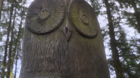 Nahaufnahme-Einer-Eulenskulptur-Im-Englischen-Wald-Mit-Sonnenlicht,-Das-Auf-Die-Skulptur-Fällt-Und-Sehr-Langsamer-Schwenk