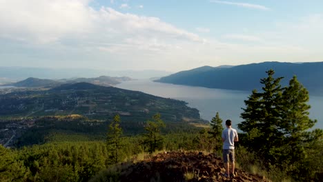 Hiker-walks-up-at-Viewpoint-in-Canadian-Mountains-overlooking-Okanagan-Lake-and-Lakecountry-in-British-Columbia's-Interior-Region