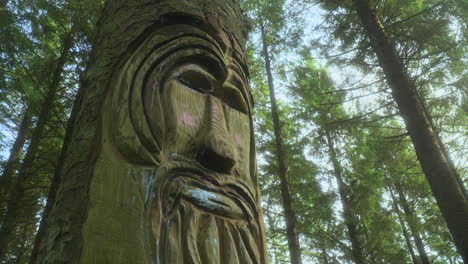 Face-carved-into-pine-tree-trunk-in-secluded-forest-with-background-trees-swaying-in-the-breeze-on-summer-day-and-very-slow-pan