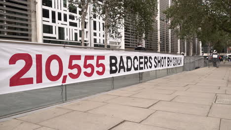 A-large-white-banner-with-red-and-black-writing-reads,-“210,555-Badgers-shot-by-Gov