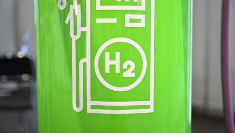 The-white-pictogram-of-a-hydrogen-filling-station-fuel-pump-on-green-background