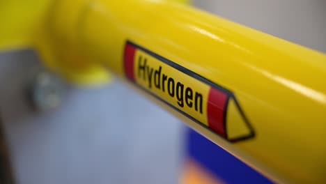 The-word-hydrogen-on-a-yellow-pipe-which-is-part-of-a-demonstrator-of-special-shut-off-valves-on-a-trade-fair,-focus-shift