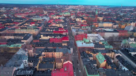Drone-Shot-of-Stockholm,-Sweden,-Flying-Above-Downtown-Buildings-and-Streets-at-Sunset