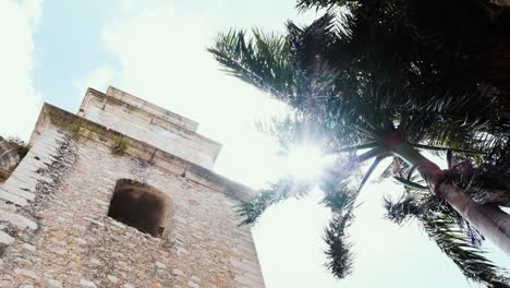 Elevated-view-capturing-a-church-and-palm-tree-in-Mérida,-framed-against-the-sky,-punctuated-with-dazzling-sun-flares