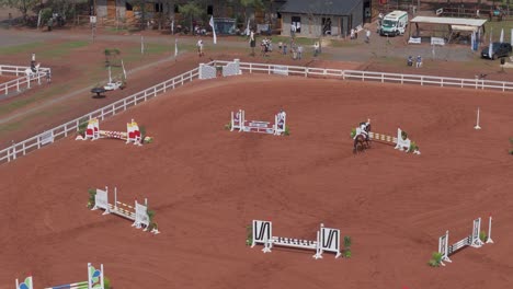 Horse-rider-performing-jumps-in-the-horse-jumping-barn-Aerial-View-of-Thrilling-Horse-Jumping-Event
