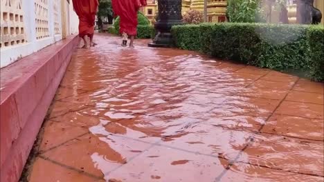 Monks-walk-home-to-theis-pagoda-after-torrential-rains-in-the-touris-hub-of-Siem-reap,-Cambodia