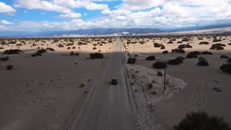 Drone-shot-following-a-grey-car-driving-towards-the-Dunes-of-Tatón-on-a-dusty-road