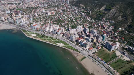 Aerial-View-of-Vlora-Coastal-City:-Stunning-Beach-Promenade-and-Bustling-Port-Along-the-Azure-Blue-Sea