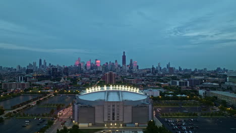 Aerial-view-backwards-away-from-the-evening-lit-United-Center,-in-gloomy-Chicago