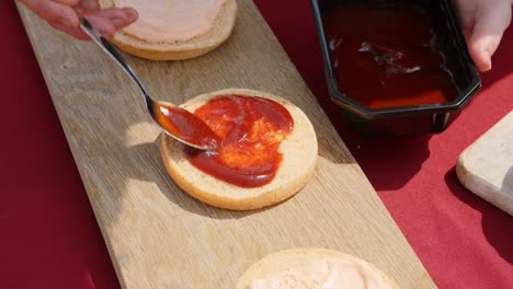 Ketchup-sauce-being-put-on-top-of-a-hamburger-bun