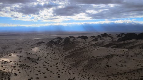 Drone-shot-flying-over-the-Dunes-of-Tatón-in-Catamarca,-Argentina-during-overcast-conditons-with-light-rays-in-the-distance