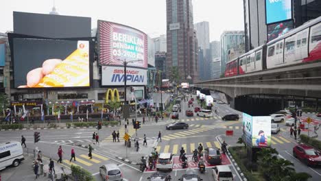 Toma-Diurna-Con-Tren-Pasando-Y-Tráfico-En-La-Concurrida-Intersección-De-Jalan-Sultan-Ismail-Y-Jalan-Bukit-Bintang-En-Kuala-Lumpur,-Malasia