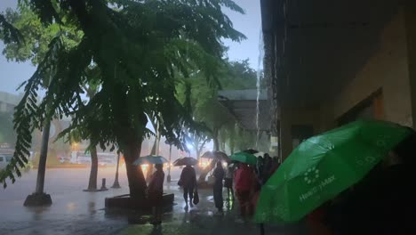 People-waiting-for-rain-to-stop-in-Bangkok-Thailand,-Monsoon-season