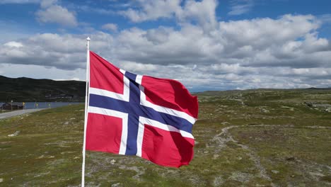 Norwegian-flag-waving-in-the-wind-in-Hardangervidda-National-Park,-Norway