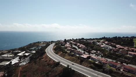 Palos-Verdes-California-Aerial-view-road-bends-houses-on-hills-coast-line-overseeing-the-ocean-beautiful-homes-tech-blue-sky-water