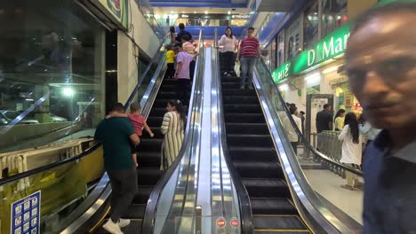 Die-Leute-Betreten-Das-Einkaufszentrum-Mit-Einem-Automatischen-Treppenaufzug-Und-Viele-Leute-Kommen-Nach-Dem-Einkaufen-Wieder-Heraus