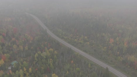 Aerial-View-of-Paved-Road-Through-Misty-Autumn-Forest