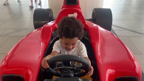 Afro-European-kid-enjoying-playing-with-red-toy-F1-car