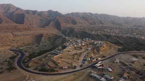 Eine-Wunderschöne,-Geschwungene-Autobahn,-Umgeben-Von-Kleinen-Dörfern-Und-Der-Gebirgskette-Des-Ormara-Hingol-Nationalparks-Im-Hintergrund-In-Belutschistan