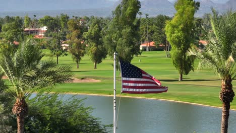 Amerikanische-Flagge-Weht-Vor-Dem-Luxuriösen-Country-Club-Golfplatz-Mit-Palmen-Im-Südwesten-Der-USA