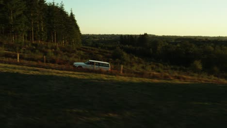 Cinematic-aerial-shot-of-Volvo-driving-through-France-landscape,-trees,-roads-and-villages