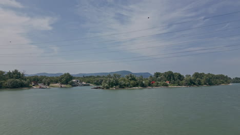 The-drone-flies-over-the-Danube,-almost-colliding-with-the-high-voltage-power-line