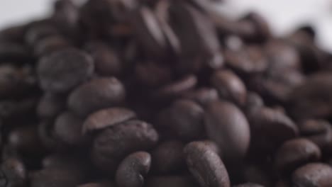 Ecuadorian-Lojano-roasted-coffee-beans-falling-in-slow-motion-onto-a-white-table,-transitioning-from-a-blur-to-a-captivating-close-up